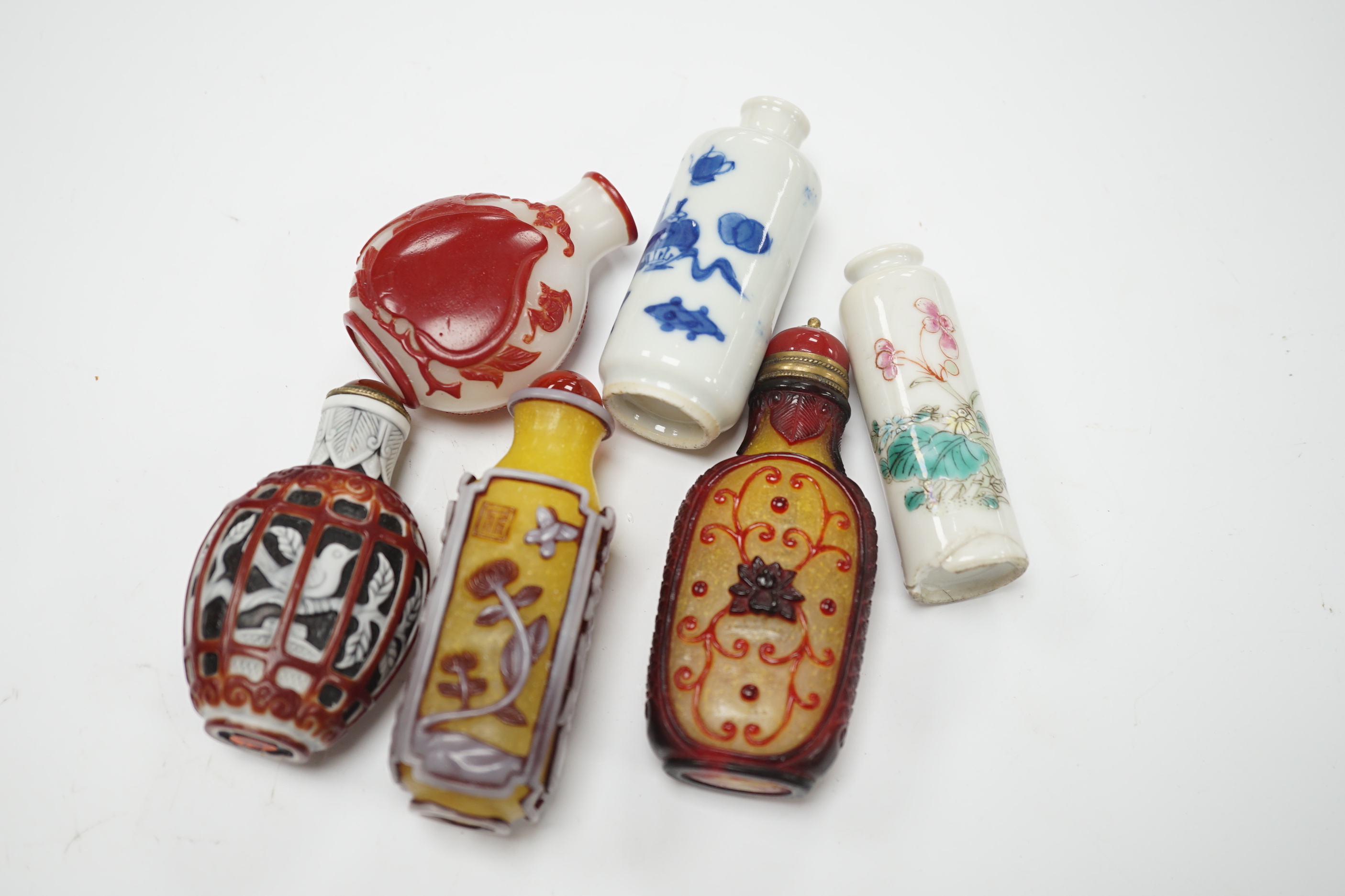 Four Chinese overlaid glass snuff bottles and two Chinese porcelain snuff bottles, three with stoppers, largest 9cm high